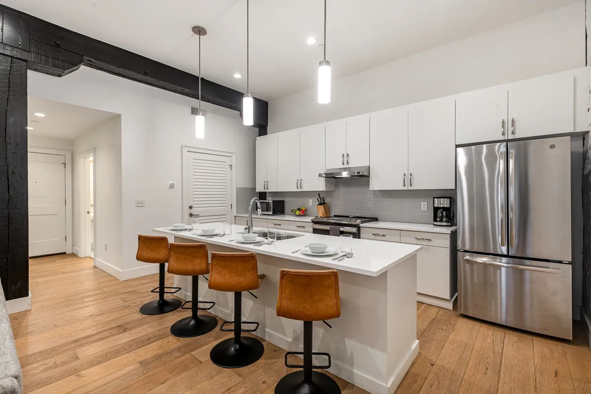 A welcoming kitchen with a spacious island, multiple bar stools, and gleaming stainless steel appliances. The setup suggests ample room for groups to gather, cook, and socialize, with the island serving as a hub for activity.