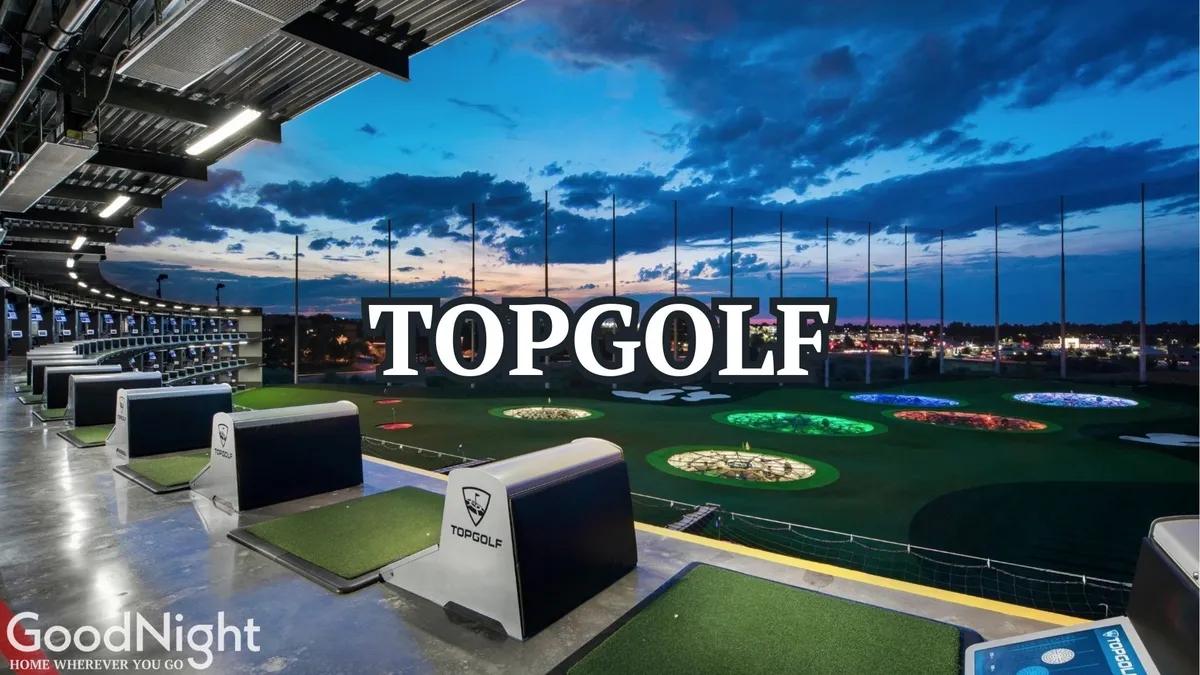 This vibrant exterior shot shows Topgolf's modern architecture, colorful target areas, and lively open sky environment. Groups of people are seen golfing and socializing, highlighting a playful, team-building atmosphere in a walkable urban setting.