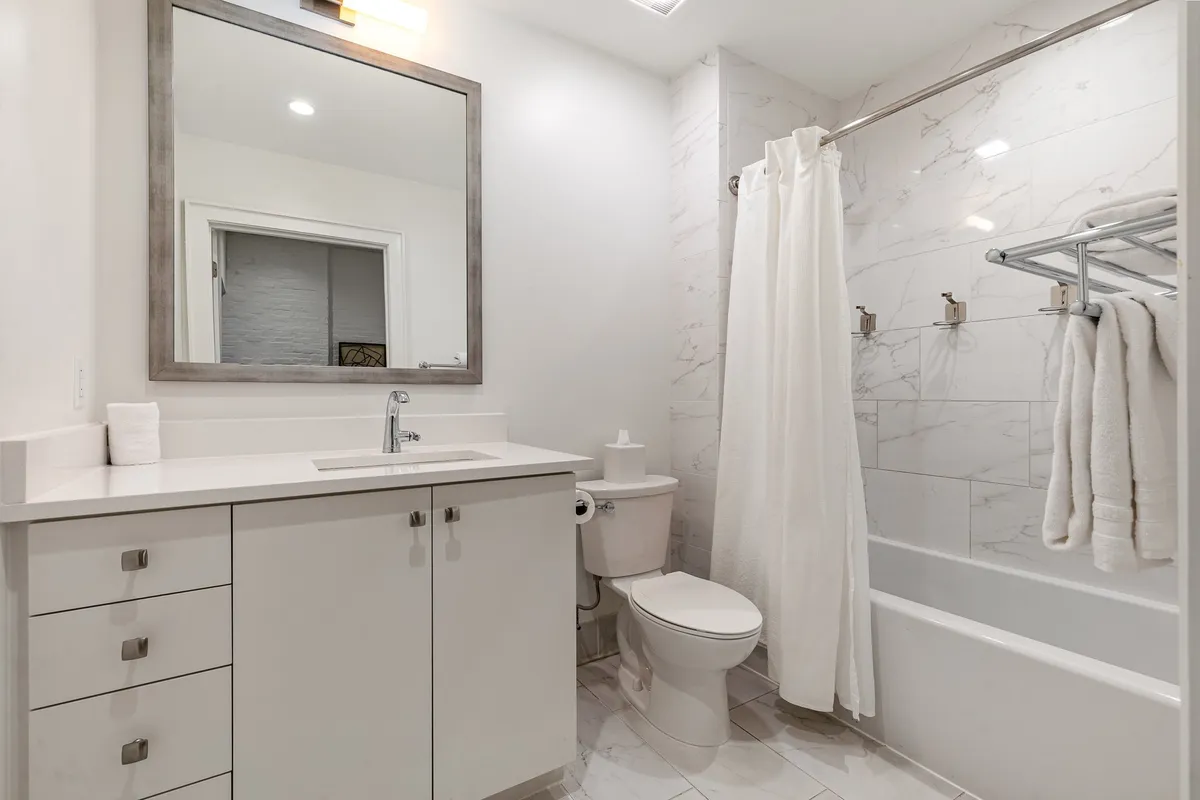 A fresh and inviting bathroom scene presenting a vanity with mirror, a bathtub, and a separate shower area. Clean lines and thoughtful design highlight the practical yet stylish amenities available.