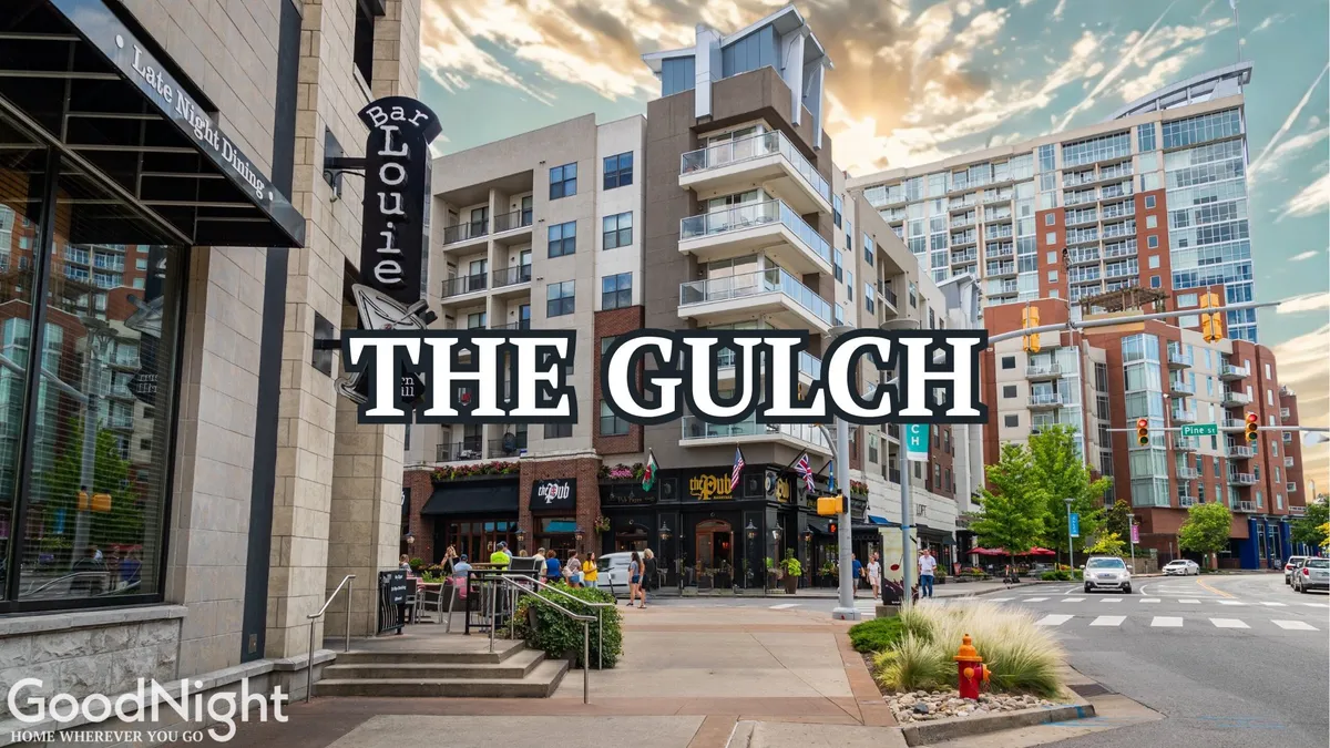 A lively streetscape view of Bar Louie and The Gulch sign, with modern apartment buildings, outdoor seating areas, and people enjoying the energetic urban environment. The daytime scene brims with life, reflecting the city's dynamic dining and nightlife options close to event venues.