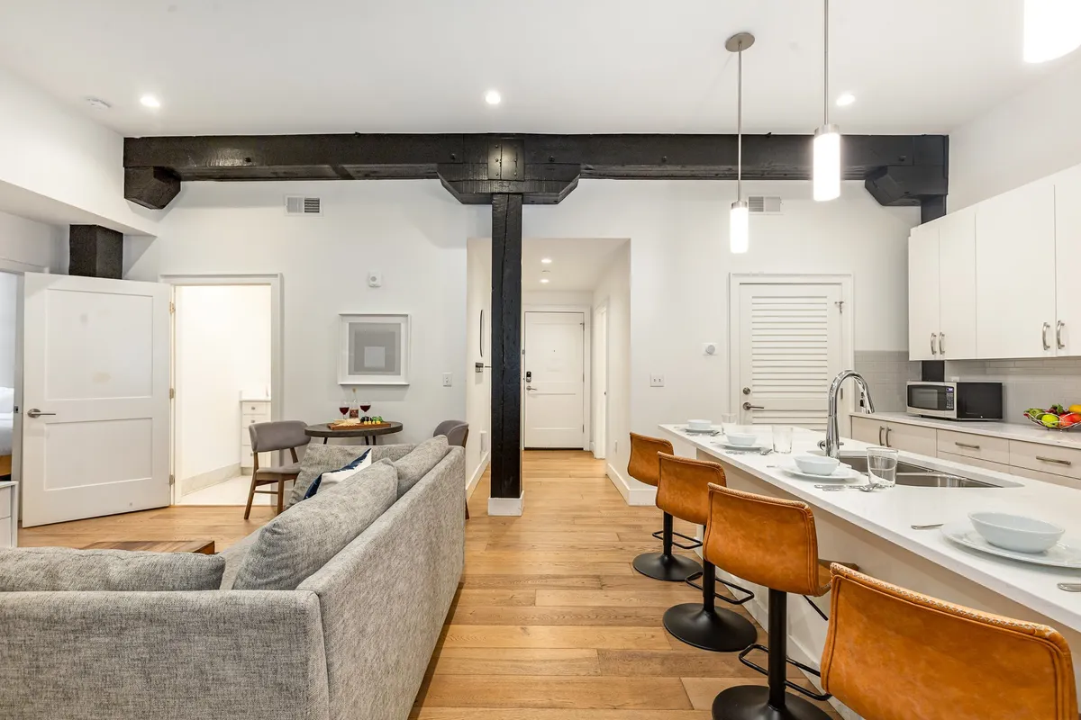 A bright and contemporary open-plan living area seamlessly combines the kitchen island, a comfortable sofa, and a dining area. Generous windows flood the space with natural light, while flexible seating encourages both relaxation and lively gatherings. The layout is ideal for group activities, from shared meals to evening recaps after a busy Nashville day.